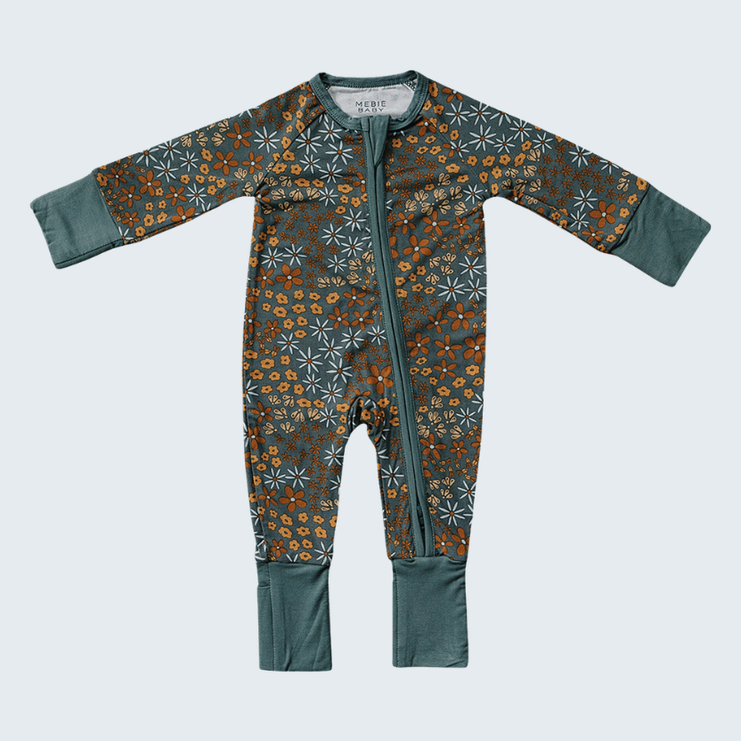 Baby onesie with floral pattern and green accents on a light gray background