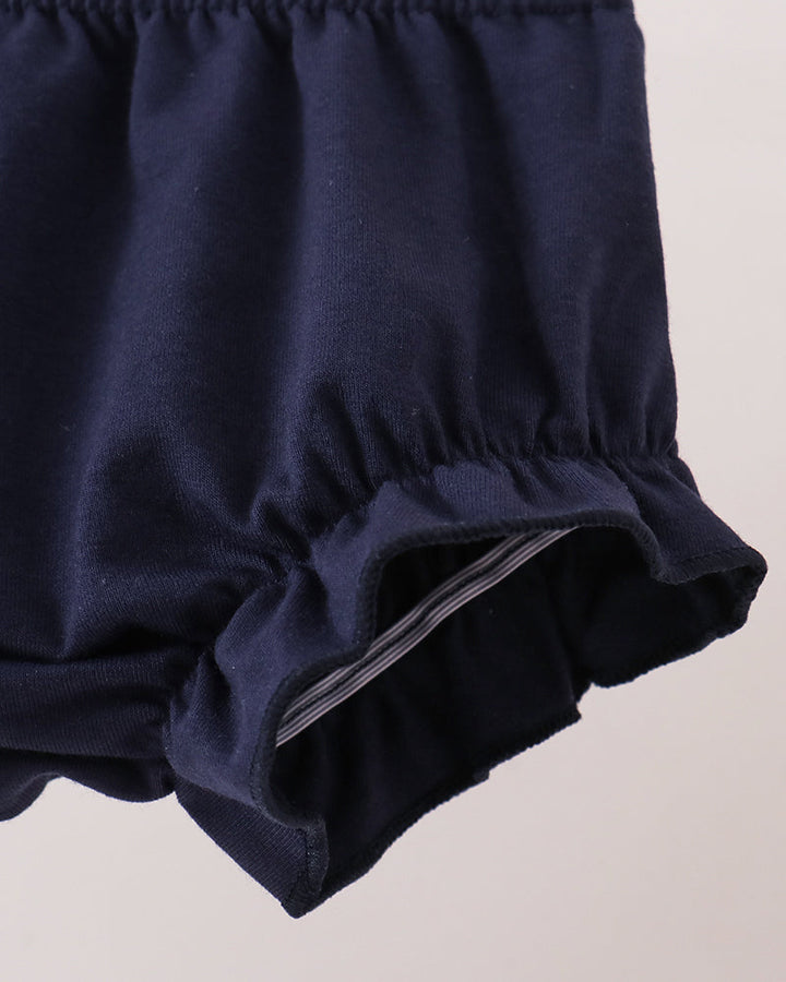 Close-up of a navy blue ruffled fabric item, showing the elasticized waistband and gathered edge against a light neutral background.