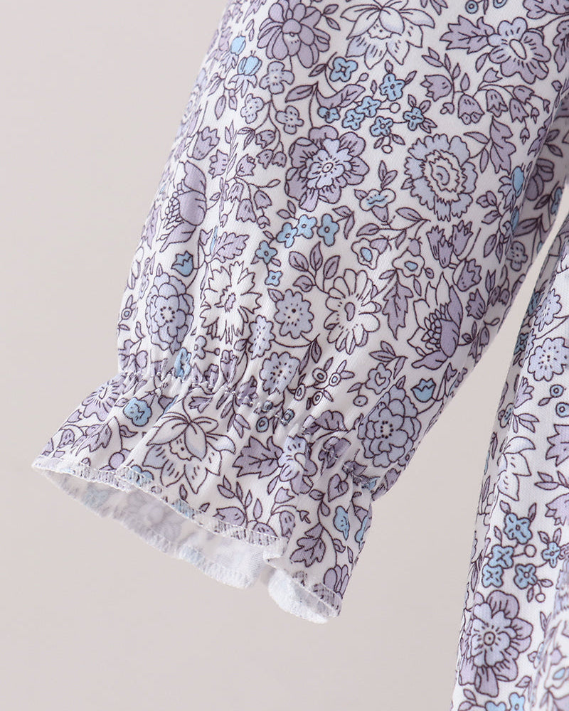Close-up of a sleeve with a white base and an all-over floral print in lavender, purple, and light blue, featuring a gathered ruffled cuff.