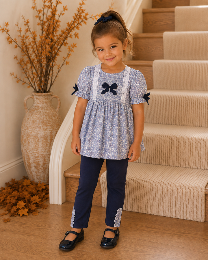 Young girl standing by a set of stairs, smiling.