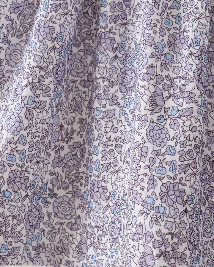 A close-up of a white fabric with an all-over floral print in lavender purple and light blue, showing the material&