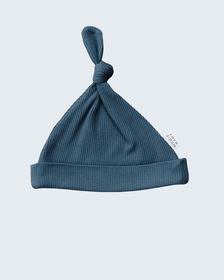 Blue baby hat with a knot on a light gray background
