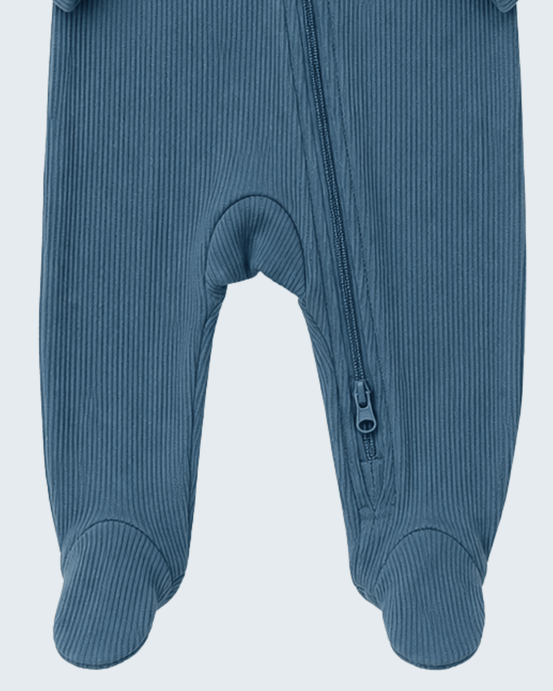 Close-up of a ribbed footed sleeper or one-piece in a muted dusty blue color, showing the zipper and leg openings on a light gray background.