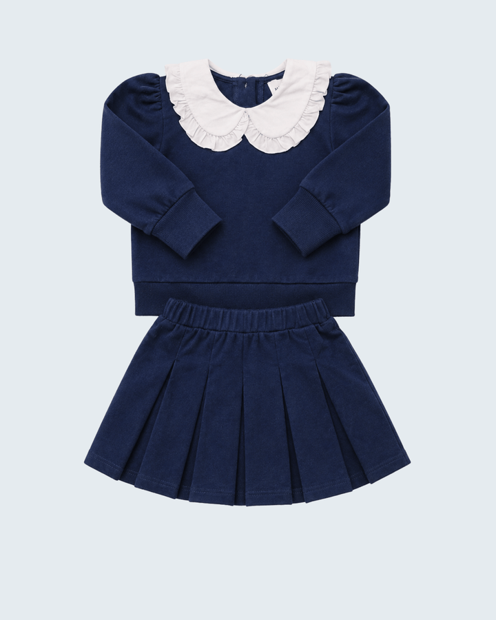 Navy long-sleeve knit top with white Peter Pan collar and navy pleated skirt