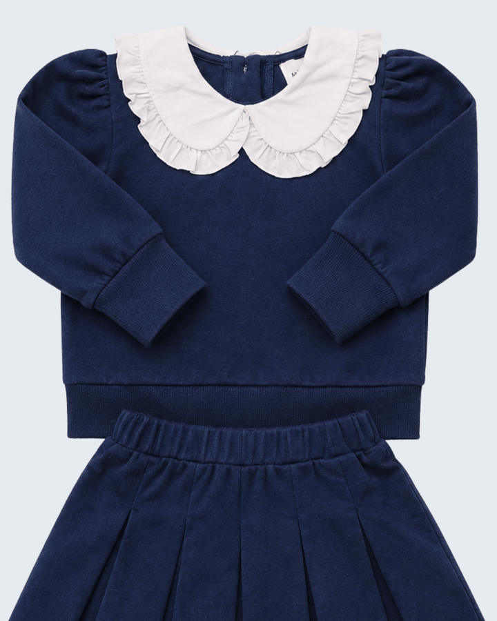 Navy knit set with white ruffled Peter Pan collar, long sleeves, and pleated skirt