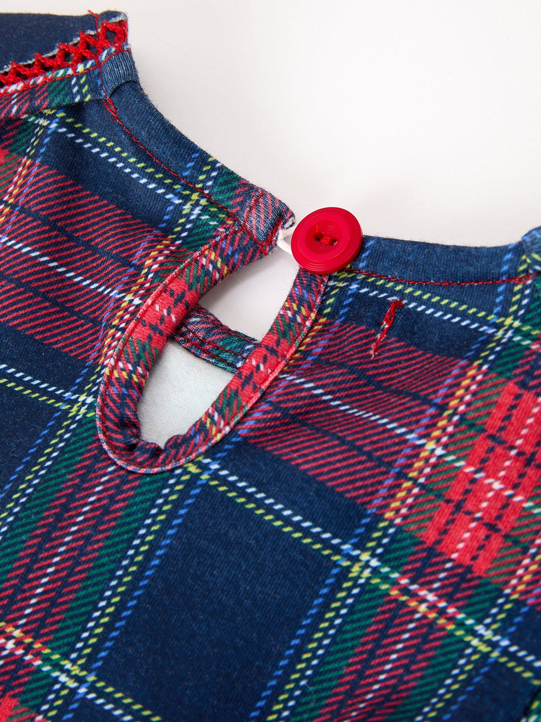 Plaid dress collar closeup with red button and scalloped neckline edge