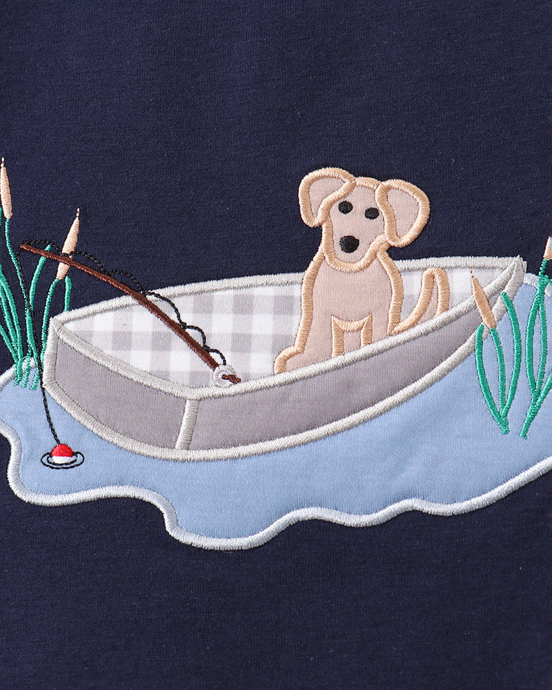 Embroidered design of a dog in a boat on a navy background