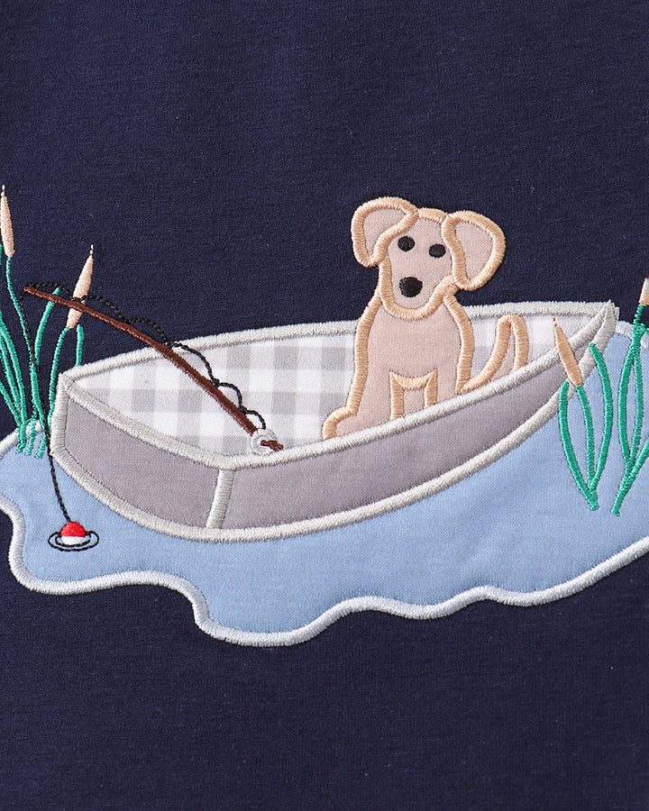 Embroidered design of a dog in a boat on a navy background