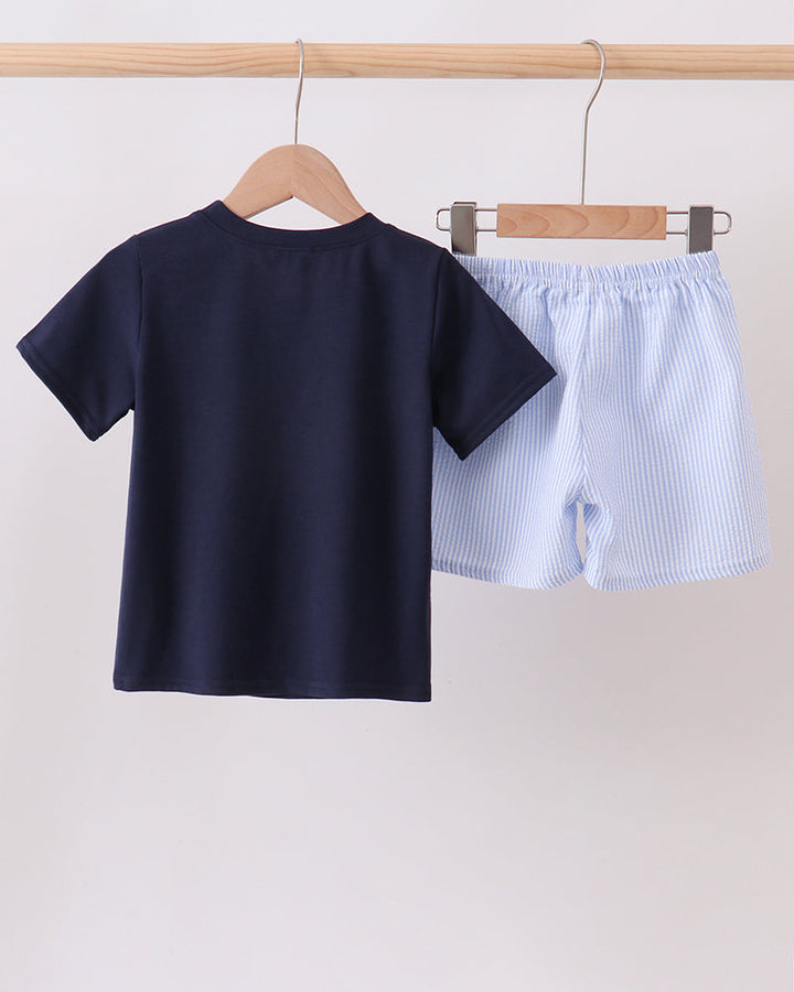 Navy blue t-shirt and light blue shorts on hangers against a white background
