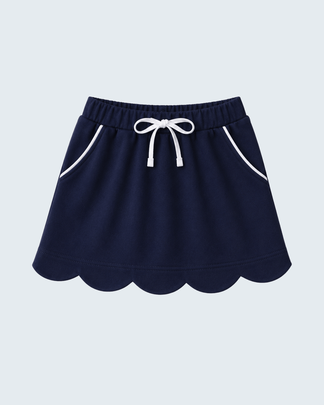 A navy blue skort with a scalloped hem, white drawstring, and white piping details on the side pockets, shown against a light gray background.