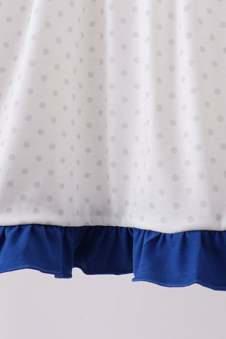 Dress with white fabric featuring gray polka dots and a blue hem on a light gray background