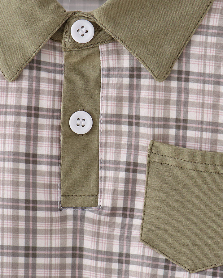 Close-up of a collared shirt with an olive green collar and placket, featuring two white buttons and an olive green chest pocket over a beige and brown plaid fabric.