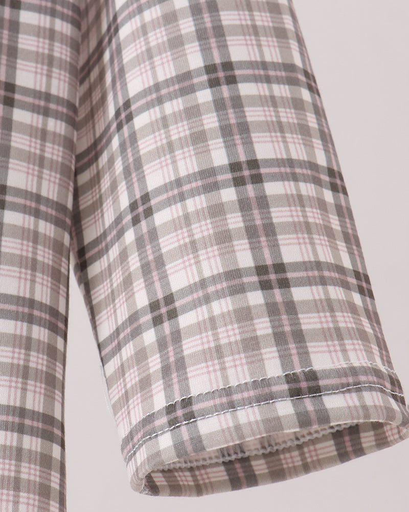 Close-up of a plaid fabric garment sleeve in a soft beige, gray, and muted pink check pattern, showing the rolled cuff and stitching against a light neutral background.