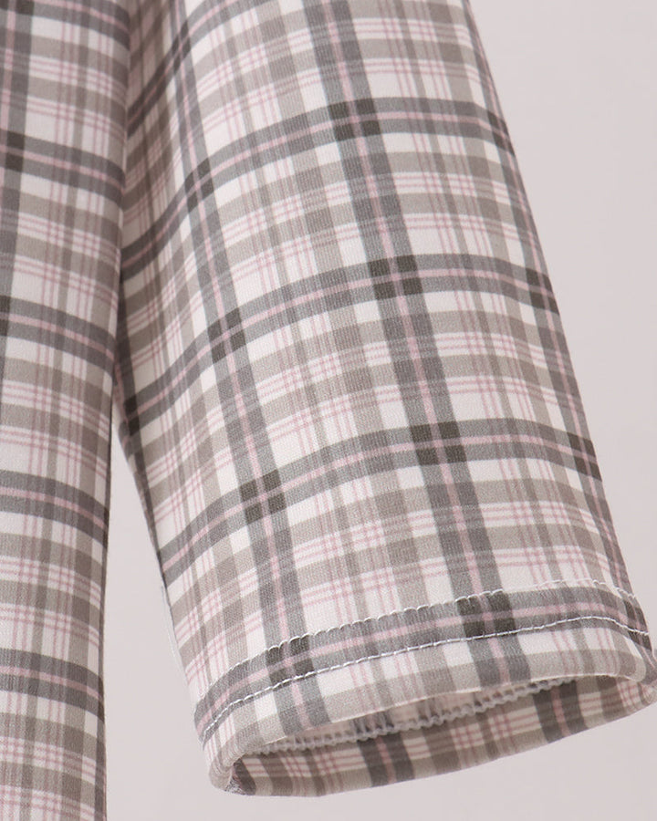 Close-up of a plaid fabric garment sleeve in a soft beige, gray, and muted pink check pattern, showing the rolled cuff and stitching against a light neutral background.