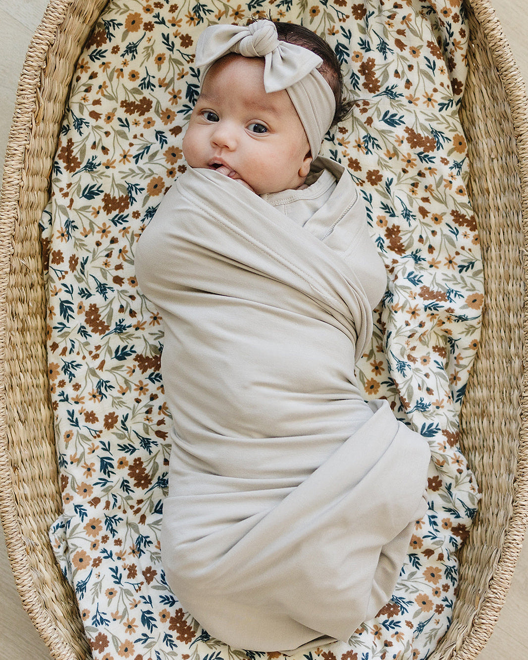Baby swaddled in bamboo wrap with oatmeal headband, knotted bow on top