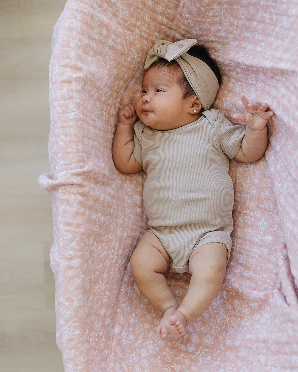 Light beige baby head wrap with knotted bow, worn on an infant