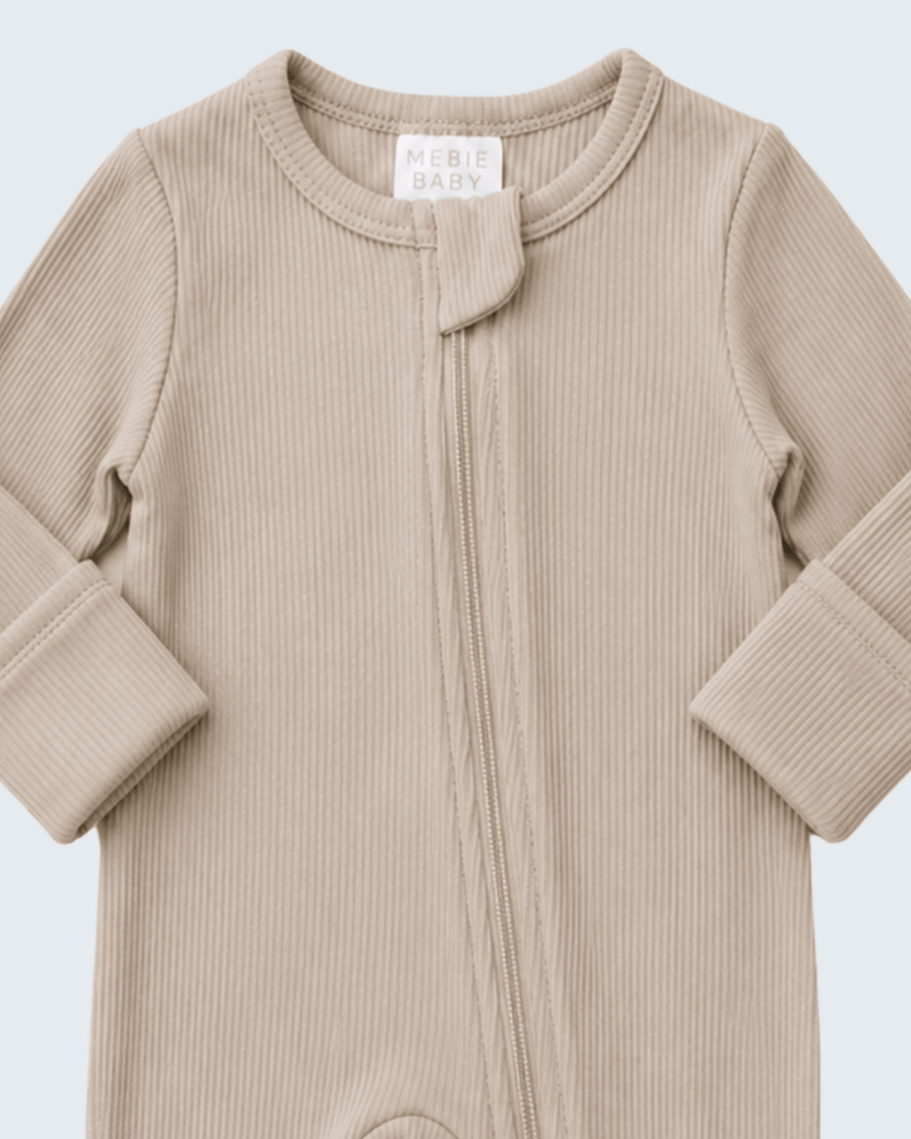 A close-up of a ribbed knit baby footless one-piece sleeper in a light beige color, featuring a front zipper and a small decorative knot at the neckline. The brand label reads 'MEBIE BABY'.