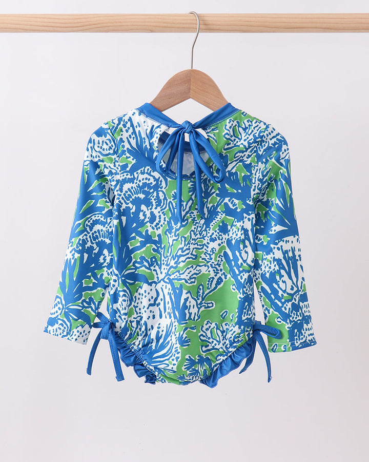 Blue and green patterned rashguard on a wooden hanger against a white background