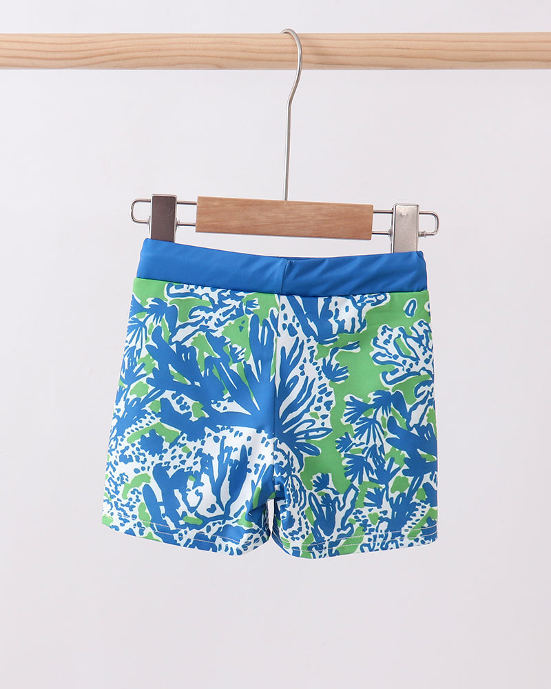 Colorful swim shorts with a pattern on a hanger against a white background