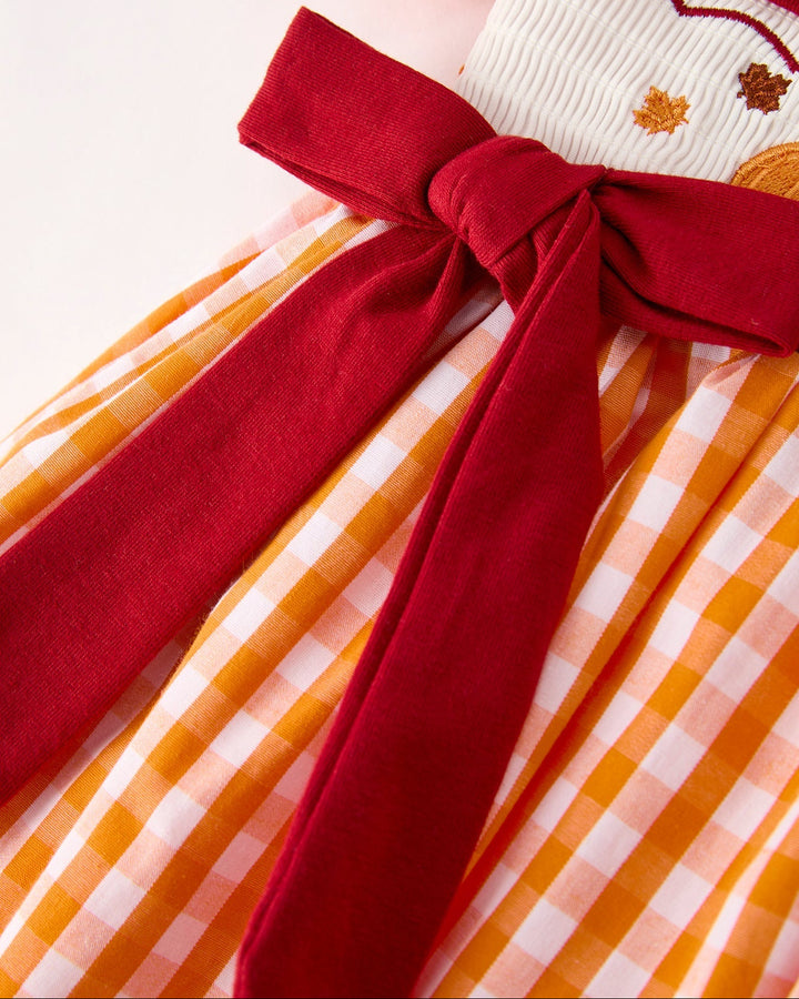 Orange checkered girls dress with wide red bow sash detail at waist