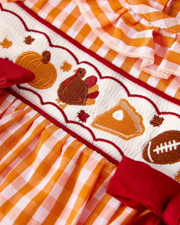 Orange gingham romper with embroidered turkey and pumpkin patches and ruffle trim