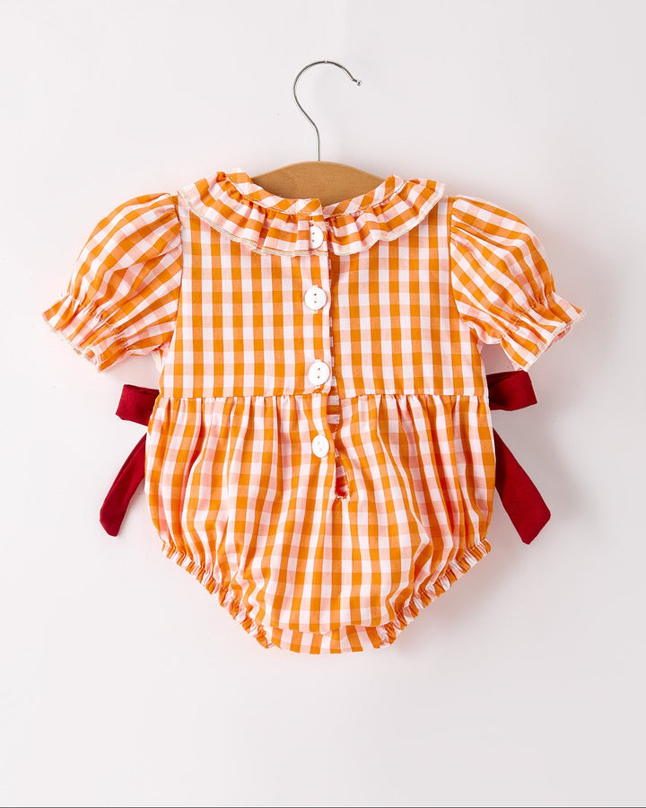 Orange checkered baby romper with short puff sleeves, button front, and red bow accents