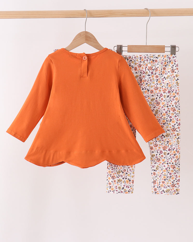 Orange henley-style long-sleeve top with floral ruffle; matching floral print pants
