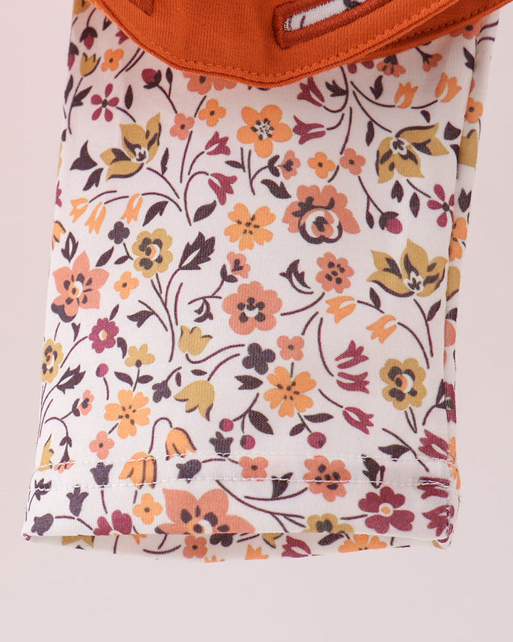 Orange long-sleeve top with floral bow and ruffle collar; floral print pants