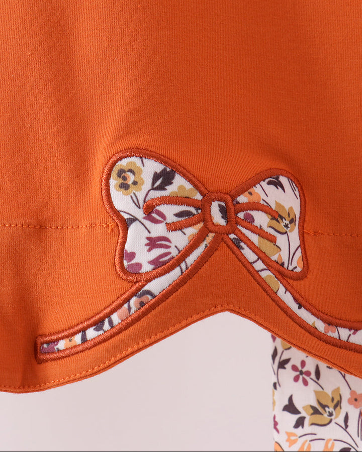 Orange top with floral bow applique and scalloped neckline trim