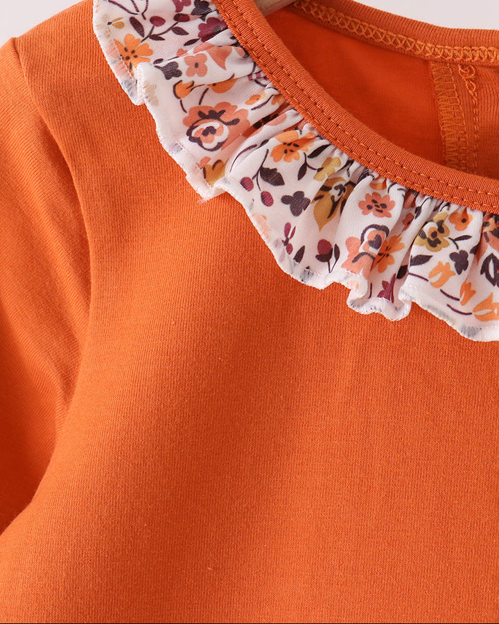 Orange long-sleeve top with floral ruffle trim at the neckline