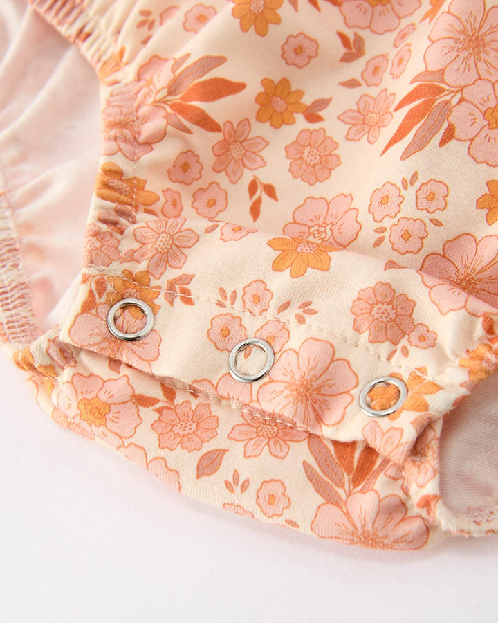 Orange floral baby romper with snap buttons and scalloped lace trim