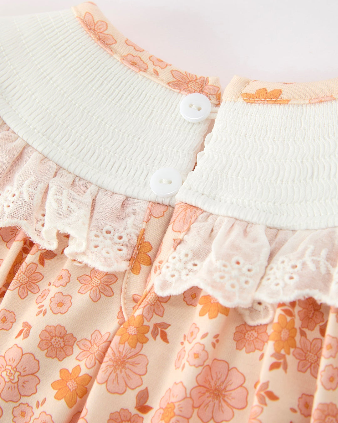 Orange floral baby romper with white elastic waist and button placket