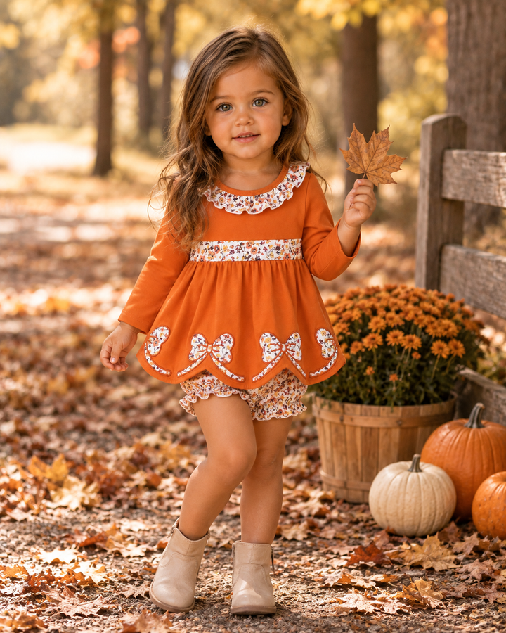 Toddler girl wearing orange ruffle dress top and floral bloomer shorts