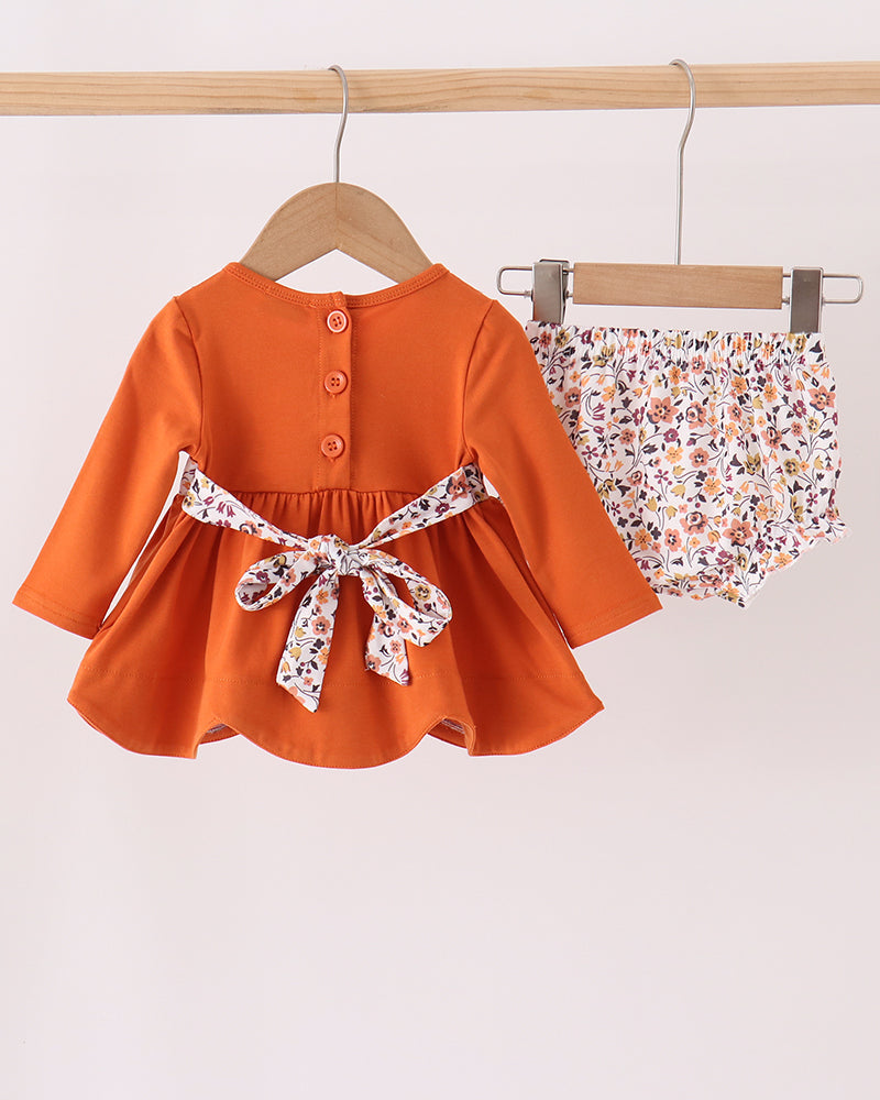 Orange long-sleeve ruffle dress top with floral bow and matching floral bloomer shorts
