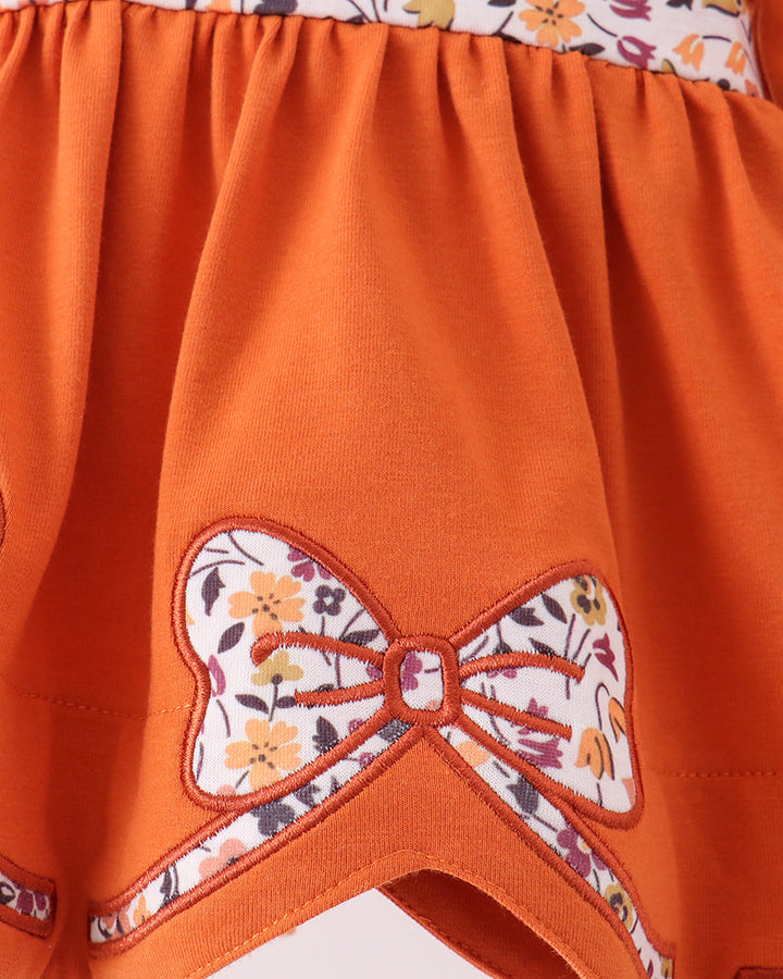 Orange dress bodice with gathered skirt and embroidered floral bow applique