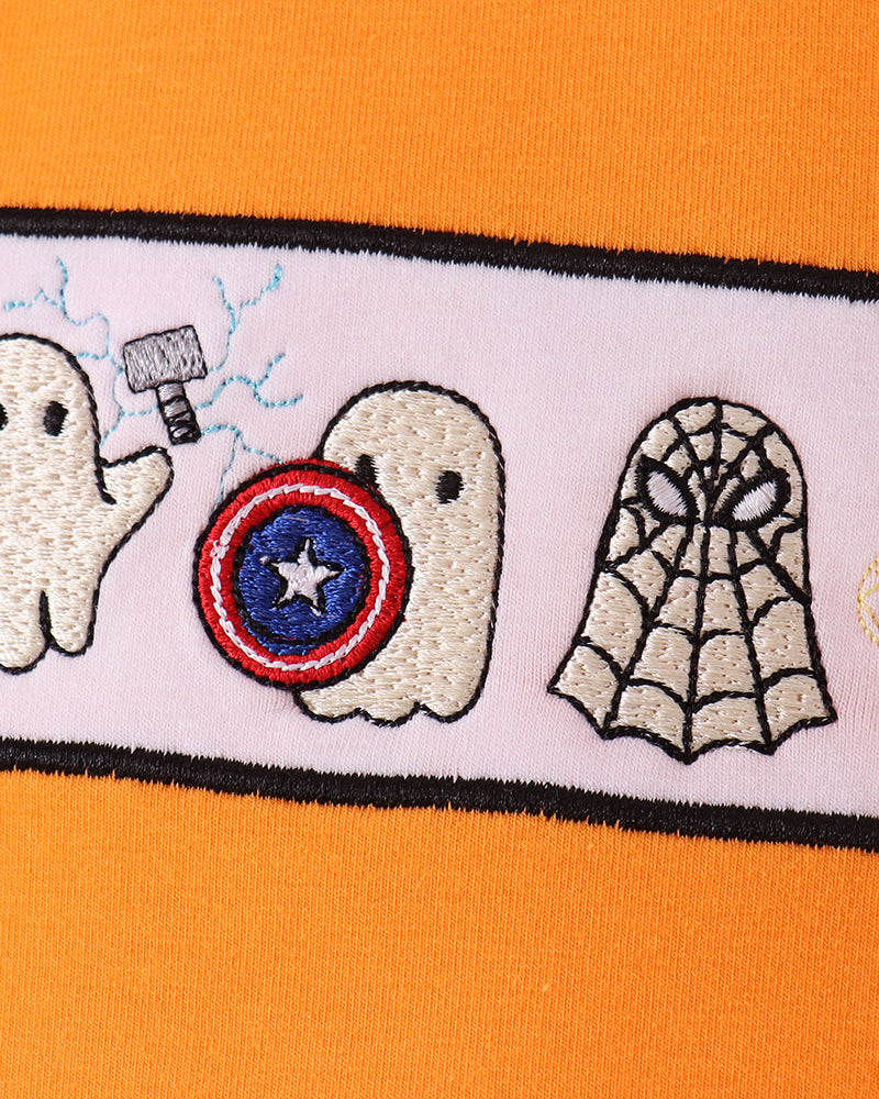 Close-up of embroidered ghosts design with star circle and spiderweb on orange top