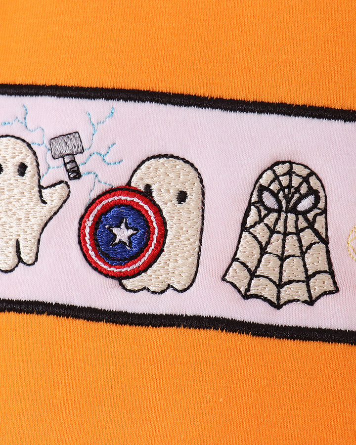 Close-up of embroidered ghosts design with star circle and spiderweb on orange top