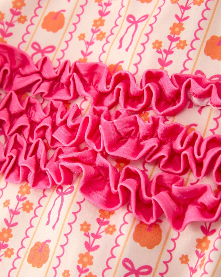 Close-up of pink ruffle detail on patterned baby sleeper fabric