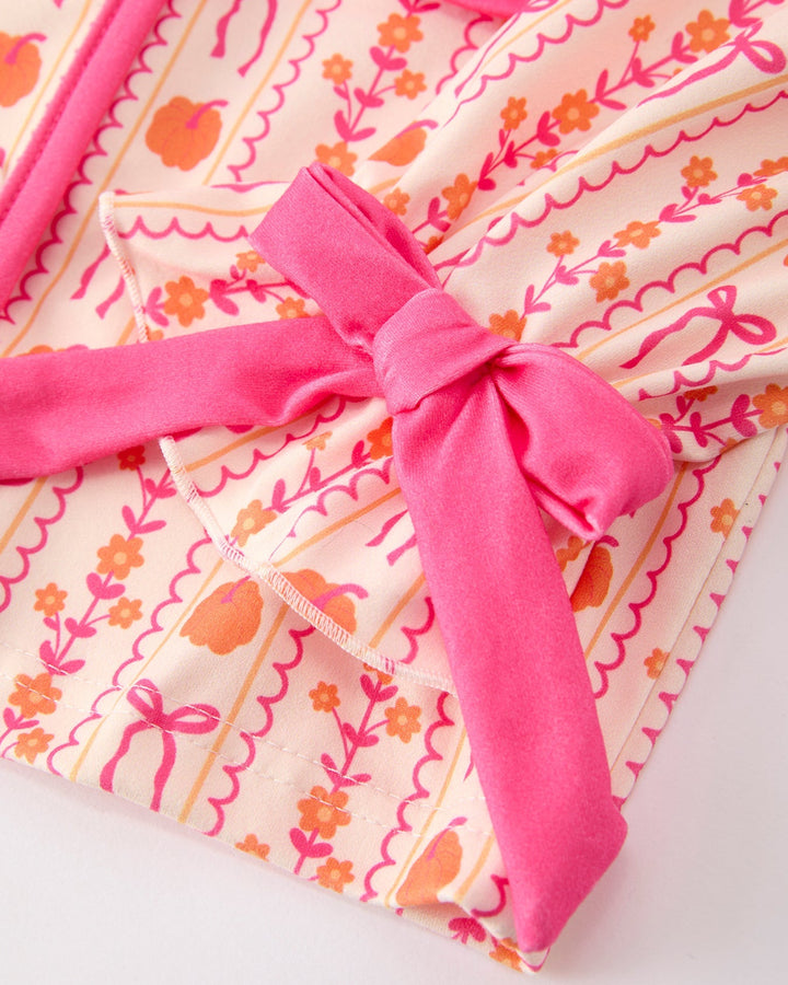 Bright pink fabric bow detail on patterned pajama top with peach and orange motifs