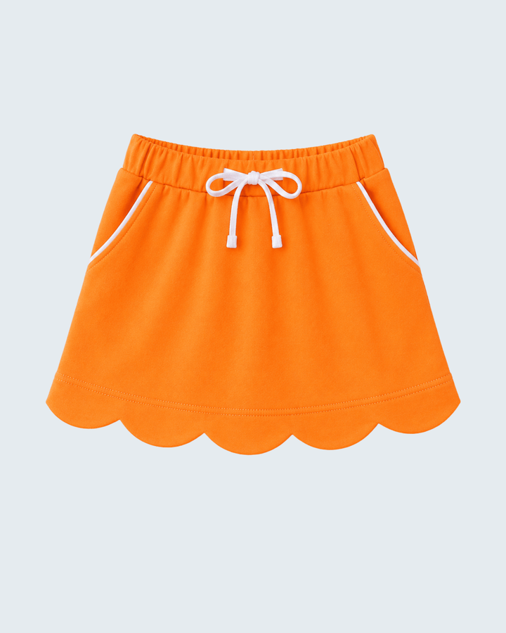 Bright orange athletic skirt with a scalloped hem, white drawstring waist, and white piping details, shown on a light gray background.