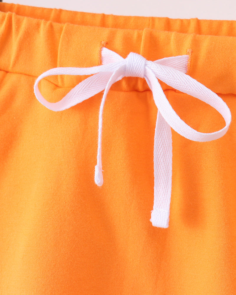 Orange skort with white bow and scalloped hem at the front