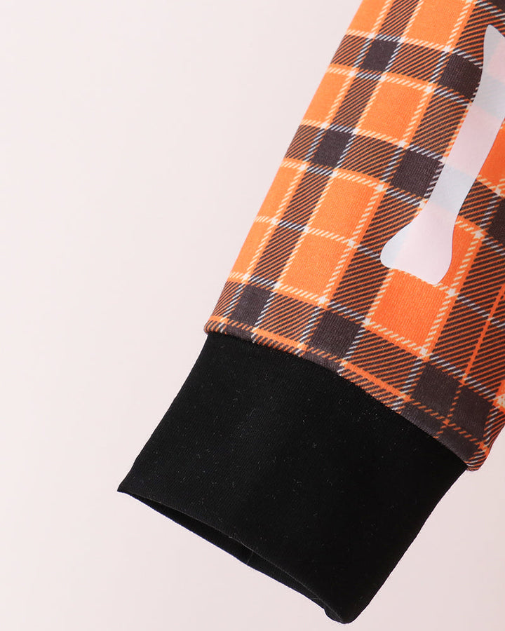 Orange plaid pants leg with black cuff and white bone applique