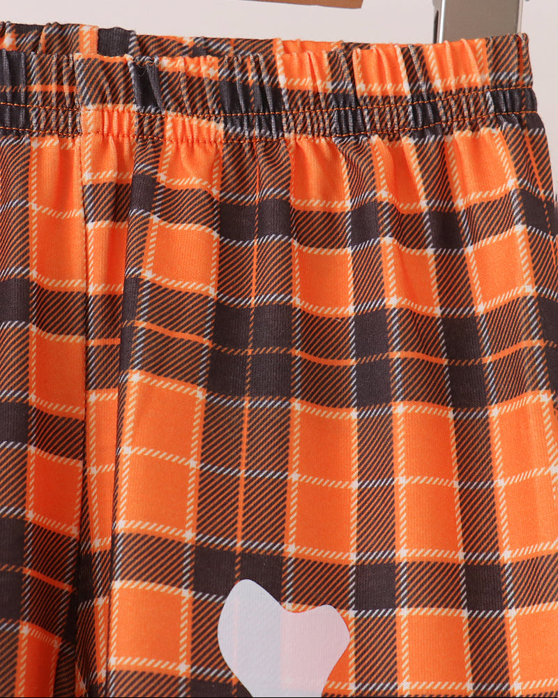 Orange plaid pants with elastic waistband and partial white skeleton bone applique
