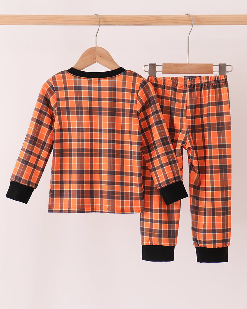 Orange plaid pajama set with skeleton print top and matching pants with black cuffs