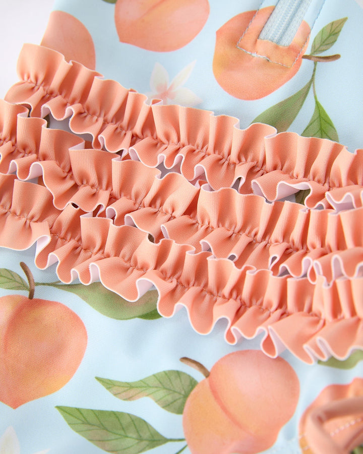 Close-up of peach-patterned fabric with ruffled texture on a light blue background.