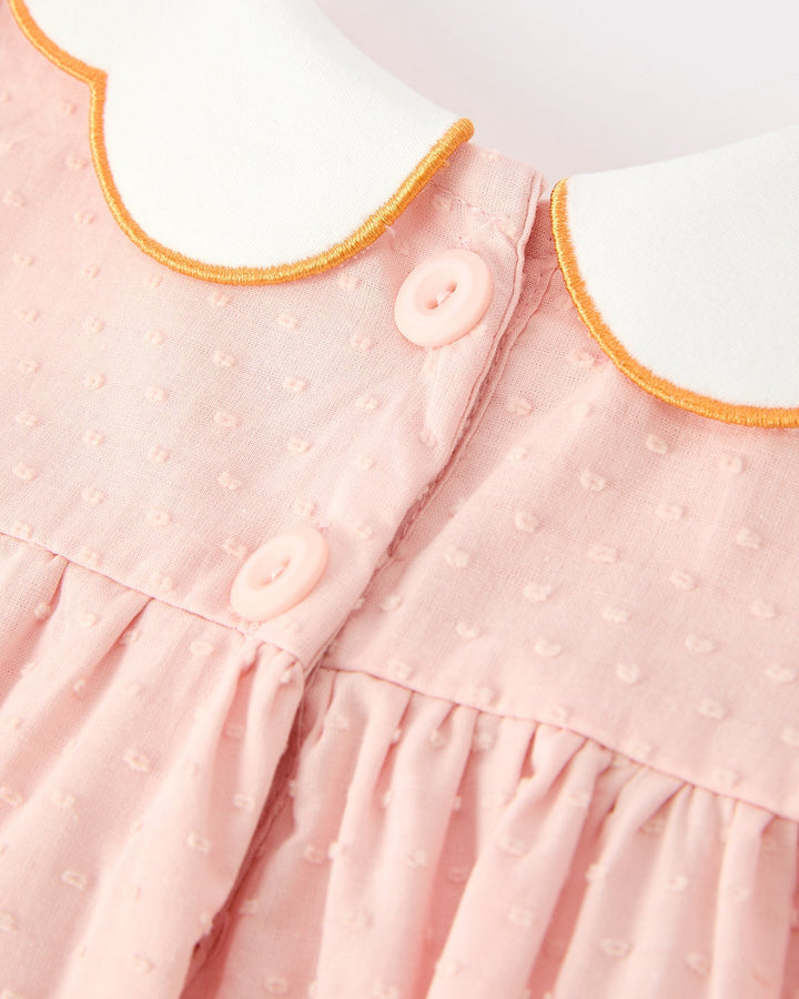 Close-up of pink button-front dress with orange scalloped collar edge