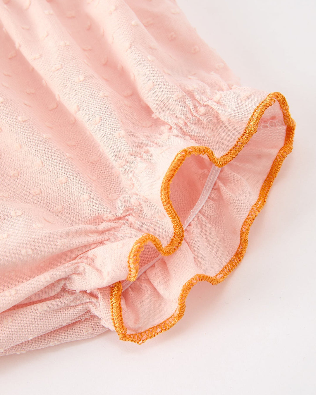 Close-up of pink girls sleeve with elastic leg openings and orange trim