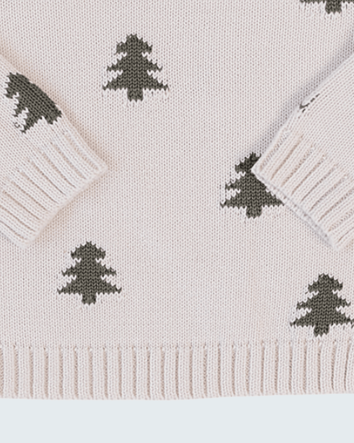 Close-up of a knit sweater in a very light blush pink with dark olive green Christmas tree motifs and ribbed cuffs, hem, and collar.