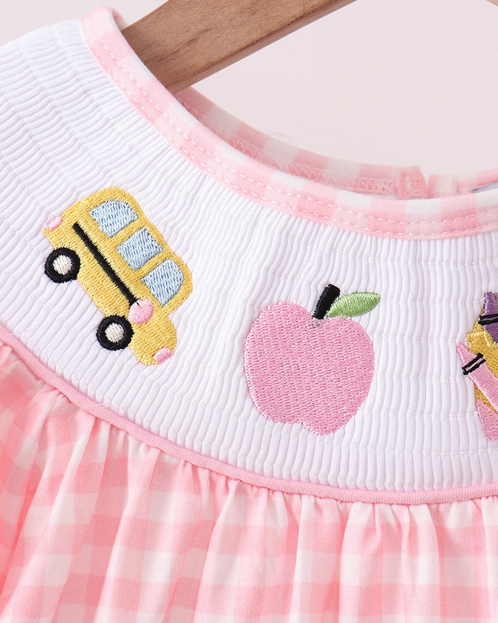 White smocked yoke dress with embroidered apple, bus, and cart patches