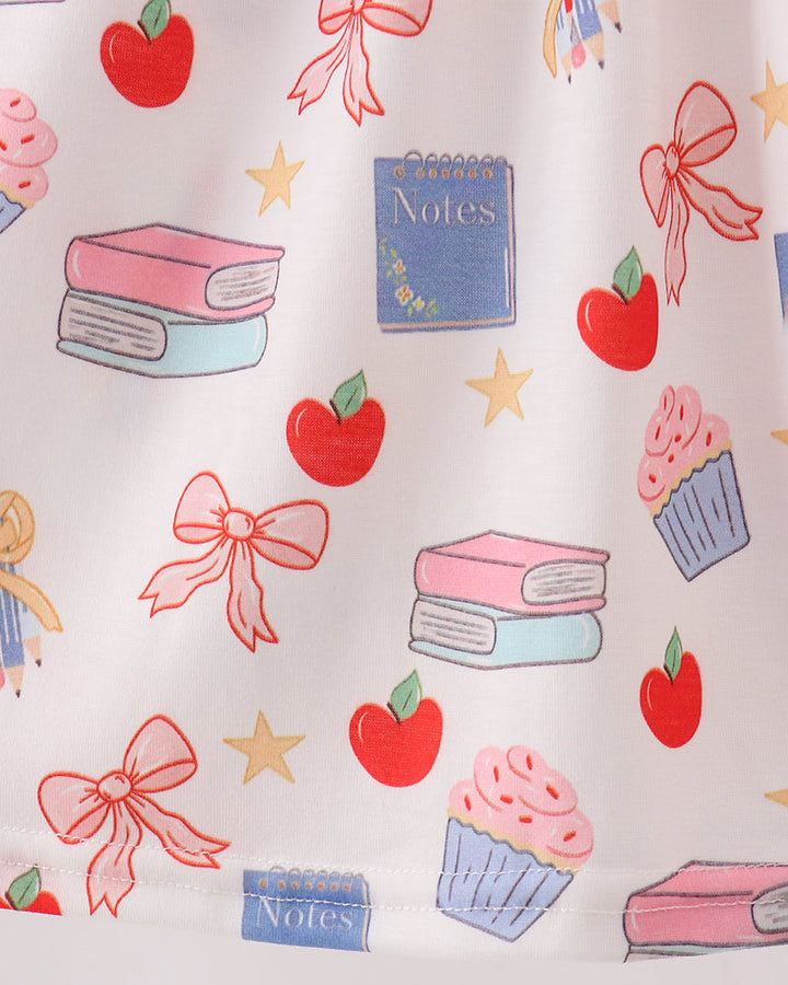 Patterned fabric with books, apples, cupcakes, and bows on a white background